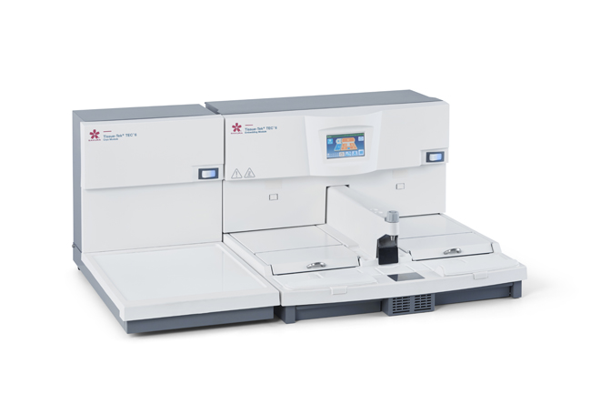 A white laboratory tissue processor with a touchscreen display and multiple compartments for sample preparation.
