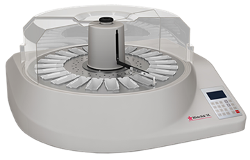 A laboratory tissue processor with a circular tray holding multiple sample containers, a transparent cover, and a control panel on the side.