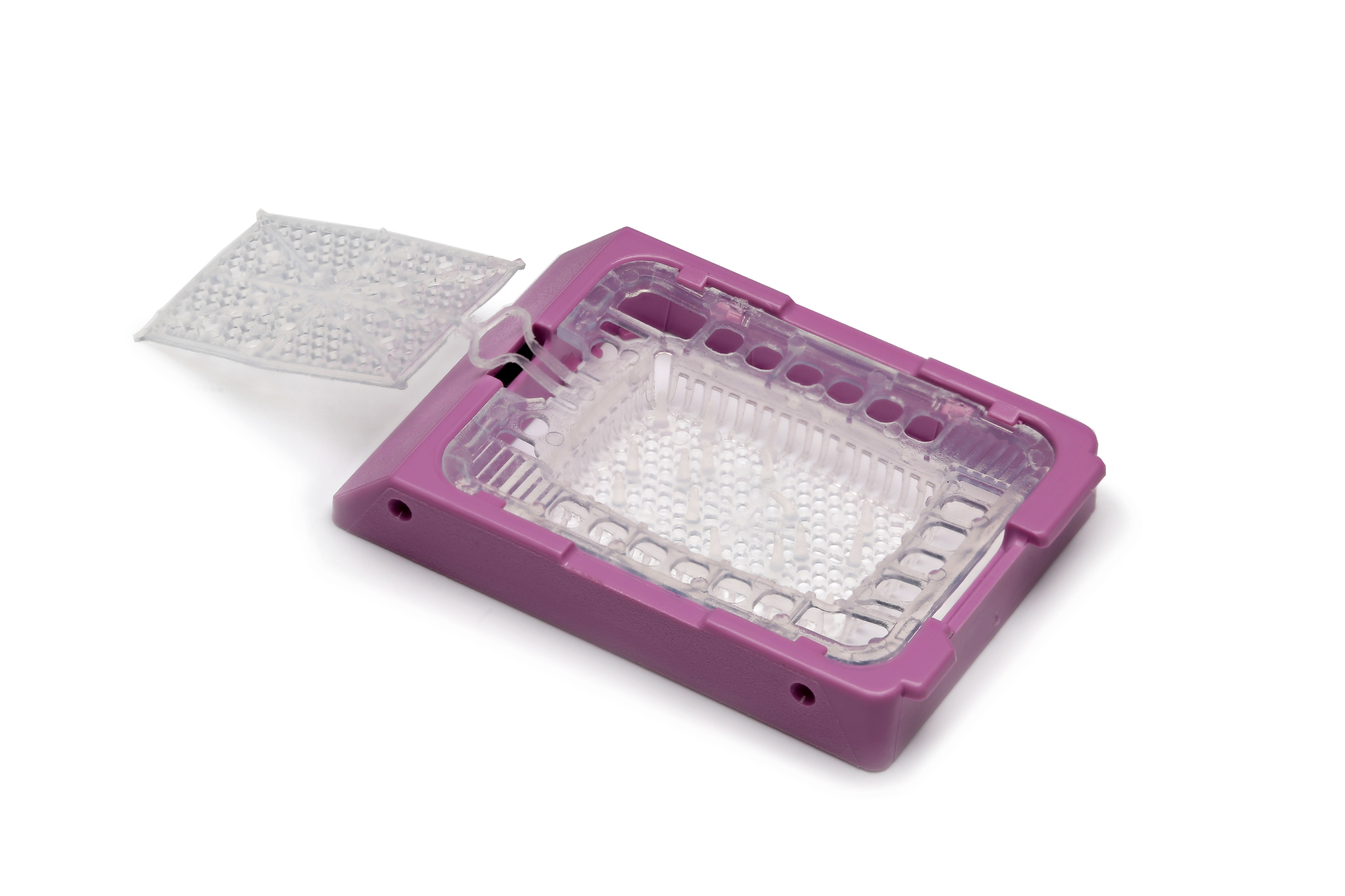 A rectangular plastic container with a transparent lid, partially open, revealing small round wells inside; the base is purple.