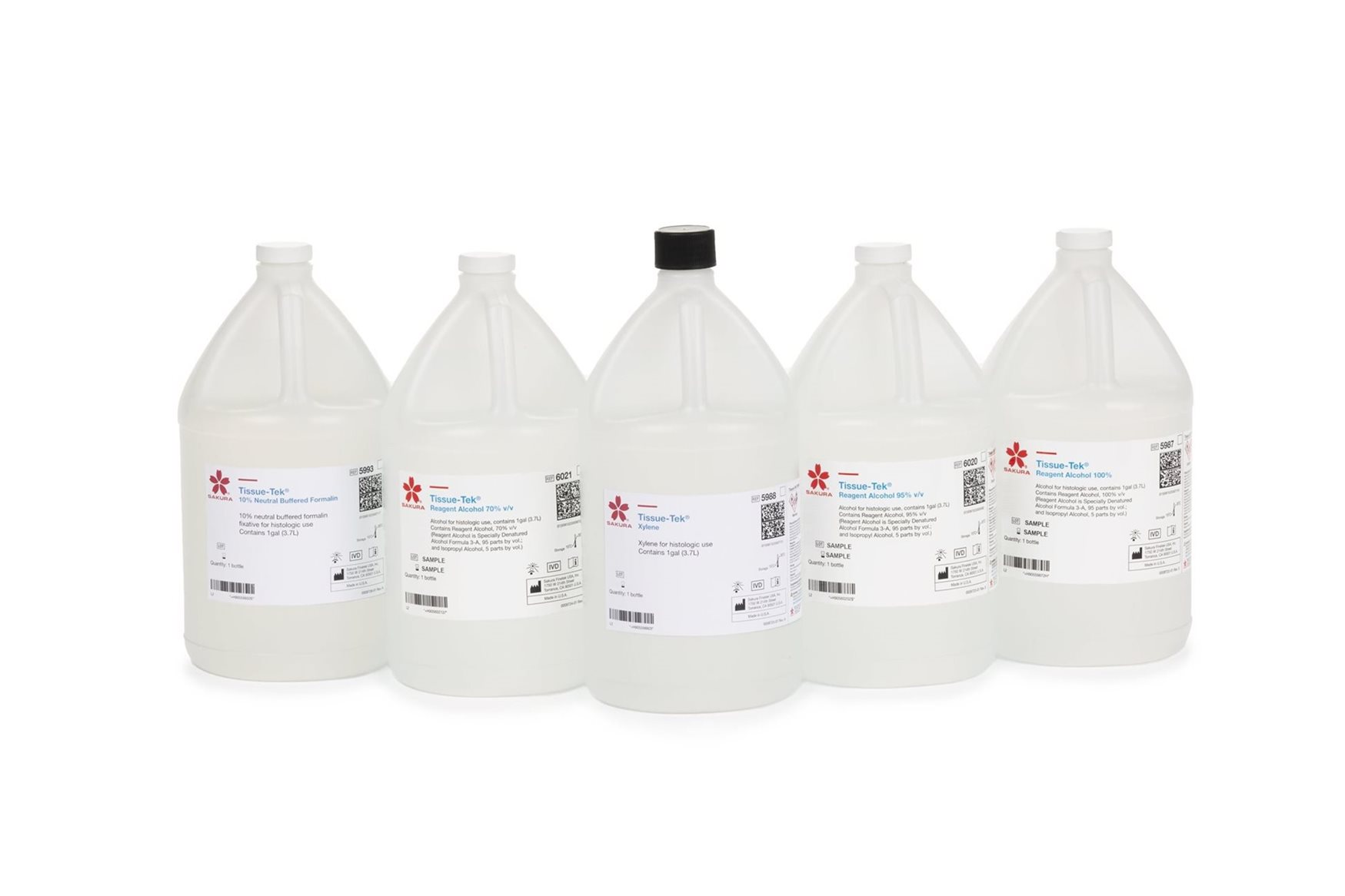 Five clear plastic gallon bottles with white labels and white caps, except one with a black cap, arranged in a row on a white background.