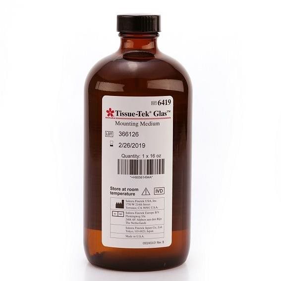 Brown bottle labeled “Tissue-Tek Glas Mounting Medium,” with product and lot numbers, date, quantity, storage instructions, and manufacturer details on the front label.
