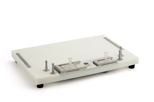 A laboratory gel casting tray with adjustable metal clamps and rulers, used for preparing gel electrophoresis samples.