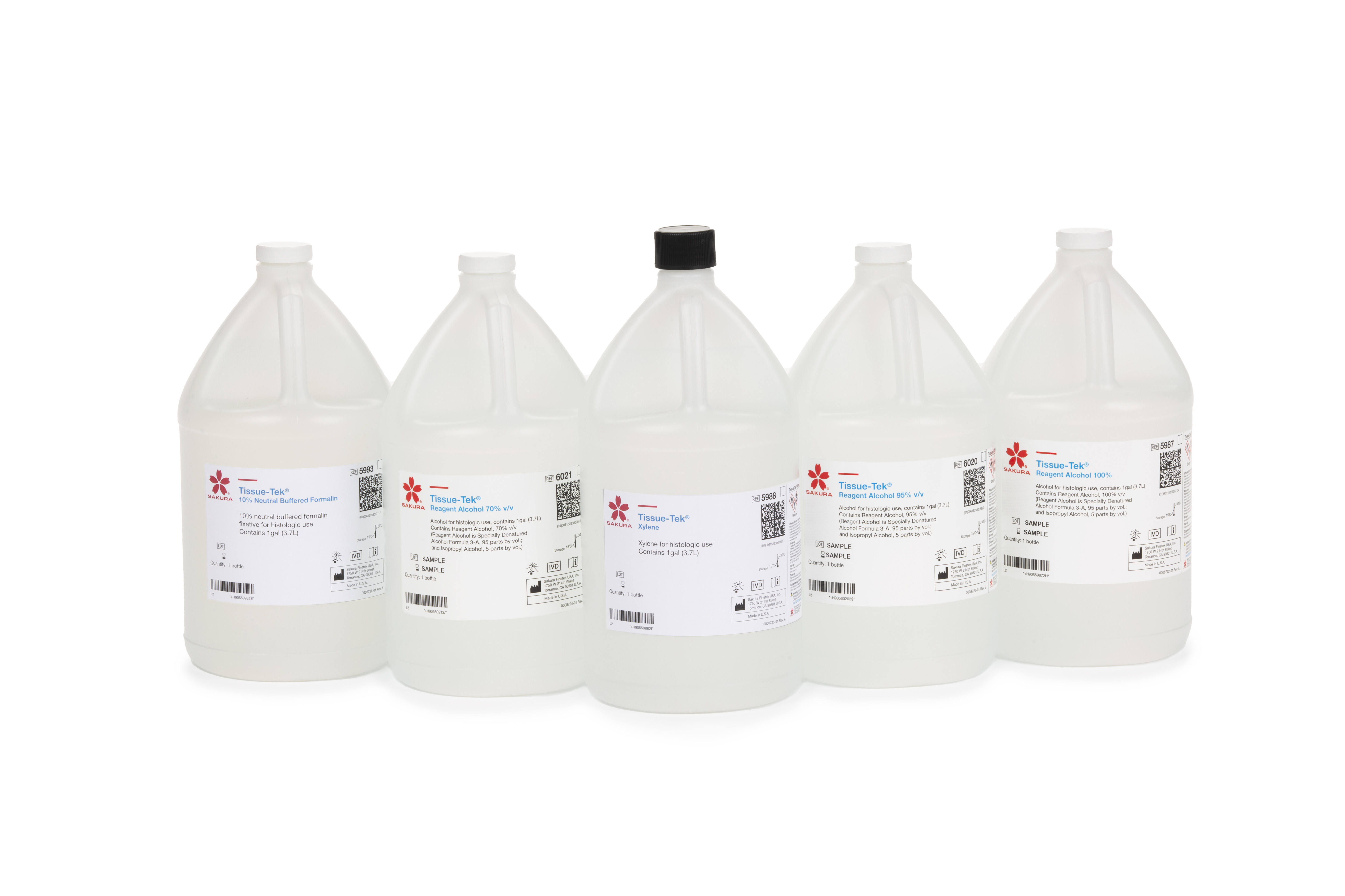 Five large clear plastic bottles with white labels and liquid inside, arranged in a row on a white background. Each bottle has a different cap color and label details.