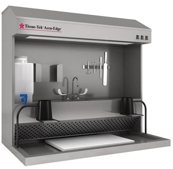 A laboratory grossing station with tools, sink, faucets, lighting, and ventilation, designed for handling and examining tissue samples.