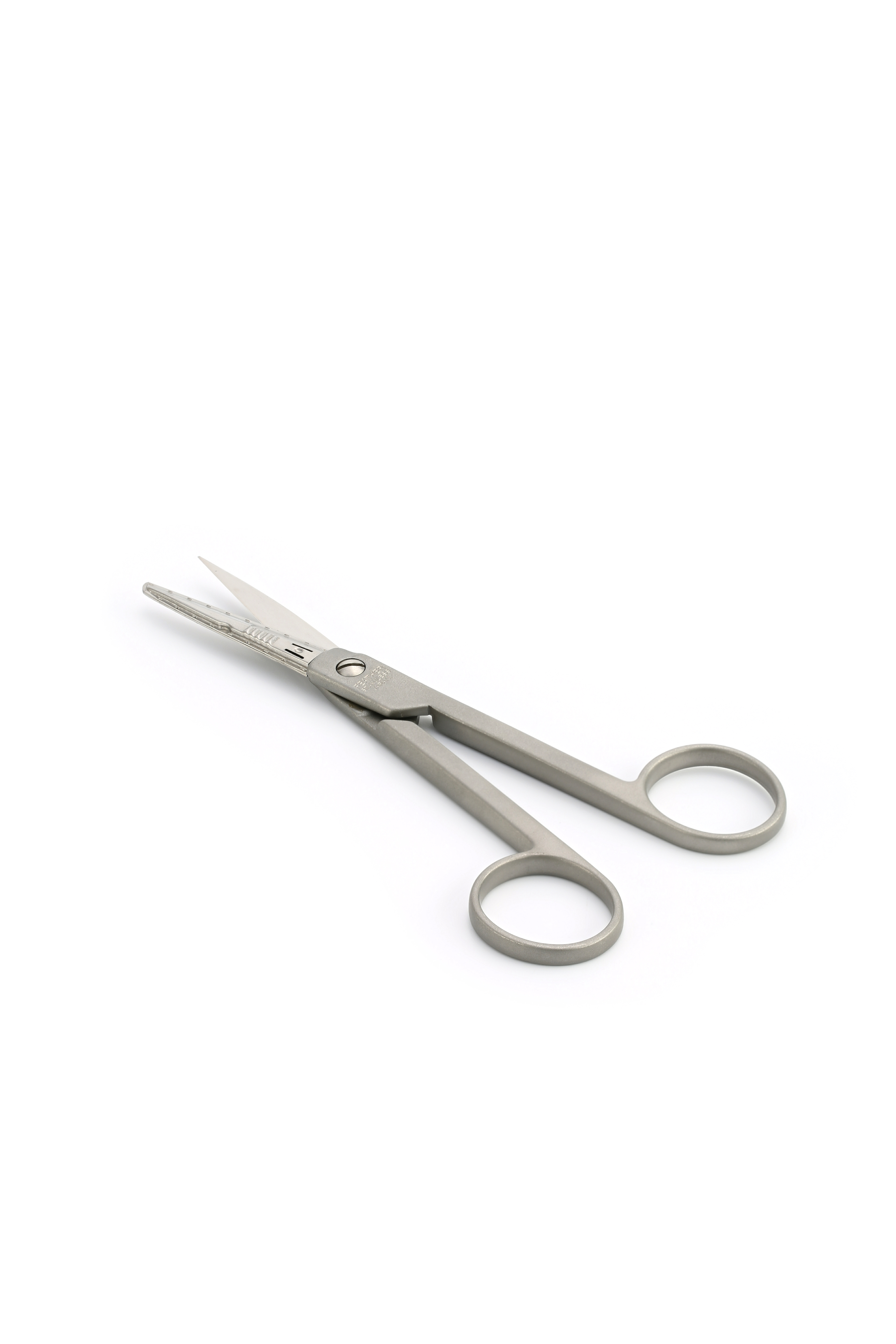 A pair of small, stainless steel scissors with rounded finger holes is placed on a white background.