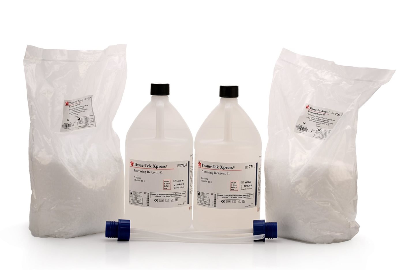 Two plastic bottles of processing reagent and two sealed bags of white powder are displayed with a blue connector tube in front.