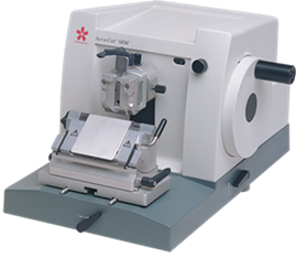 A laboratory microtome with a handwheel and specimen holder used for cutting thin sections of samples for microscopic examination.