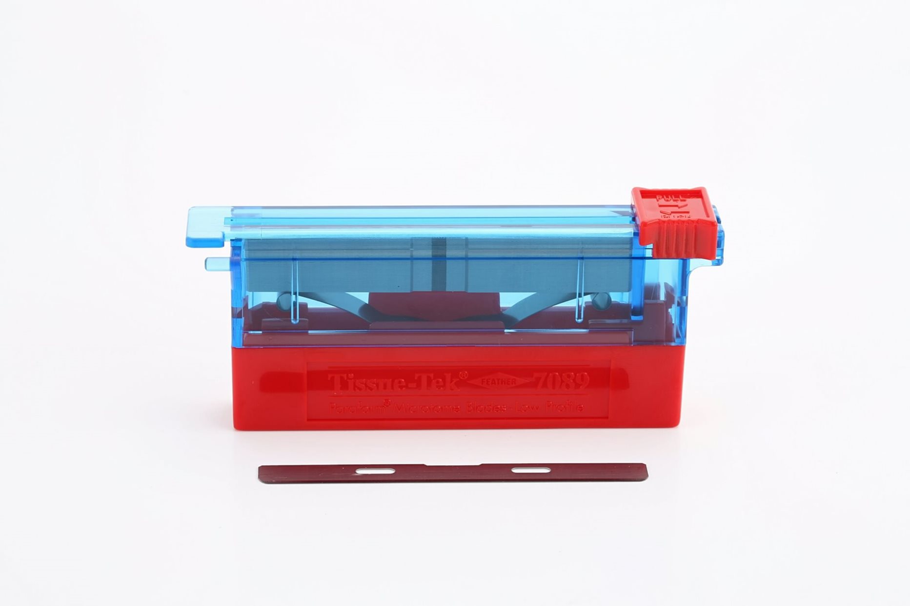 A red and blue plastic tissue cassette holder with a detached black blade placed in front, shown on a white background.