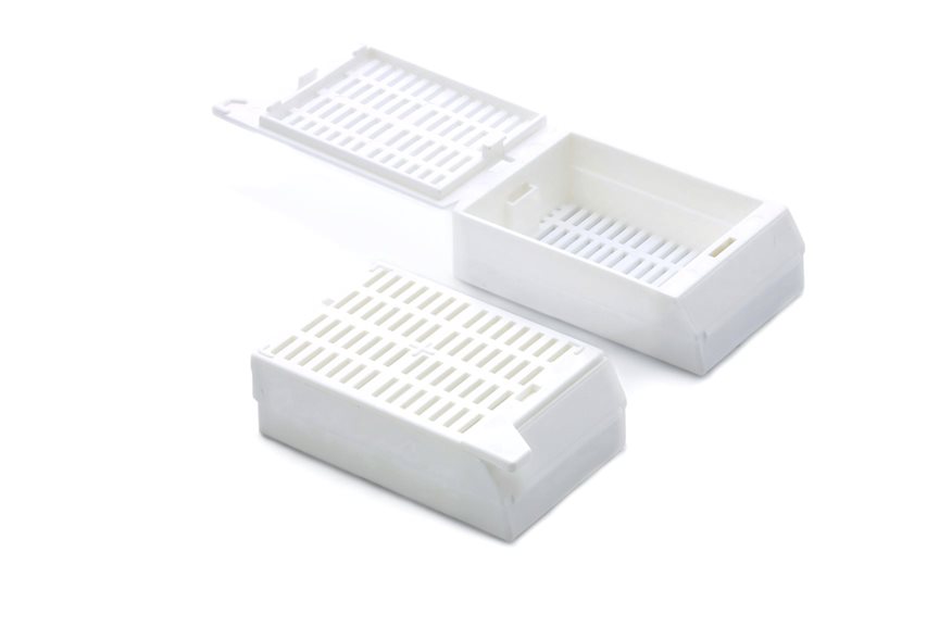 Two white plastic tissue cassettes, one with the lid open and one closed, are displayed on a white background.