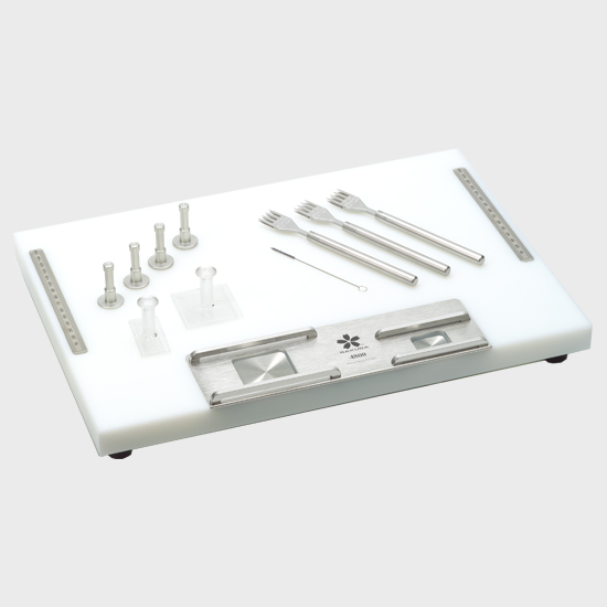A set of metal laboratory instruments and tools arranged on a white rectangular tray with a metal base and measuring guides.