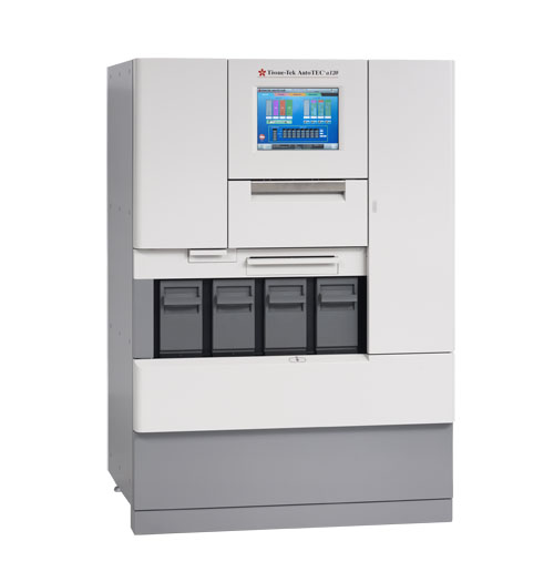 A large medical laboratory analyzer with a central touchscreen display and four black cartridge slots at the bottom, used for automated sample processing.
