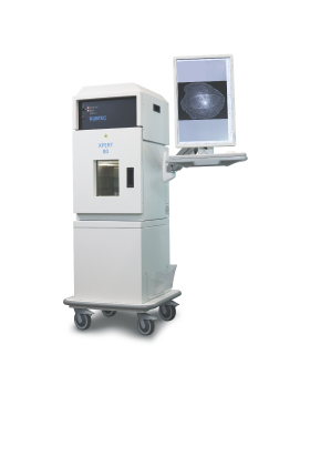 A medical imaging machine on wheels displays a black-and-white scan of breast tissue on an attached monitor.