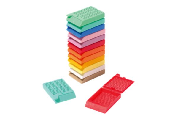 A stack of multi-colored plastic cassette biopsy embedding molds, with two molds open and lying flat in the foreground.