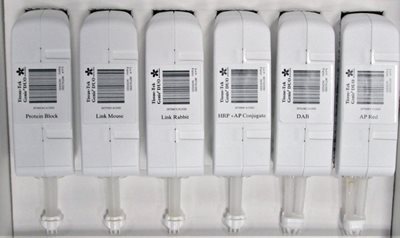 Six labeled reagent cartridges with attached syringes are aligned vertically in a holder, each labeled for different laboratory uses such as Protein Block and DAB.