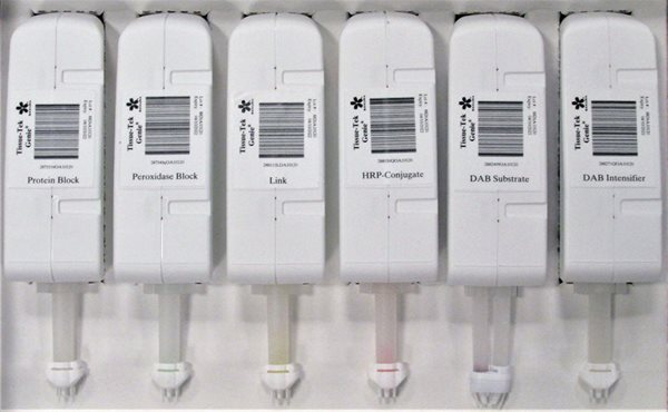 Six labeled cartridges, each with a barcode and a descriptive label: Protein Block, Peroxidase Block, Link, HRP-Conjugate, DAB Substrate, and DAB Intensifier, arranged side by side.