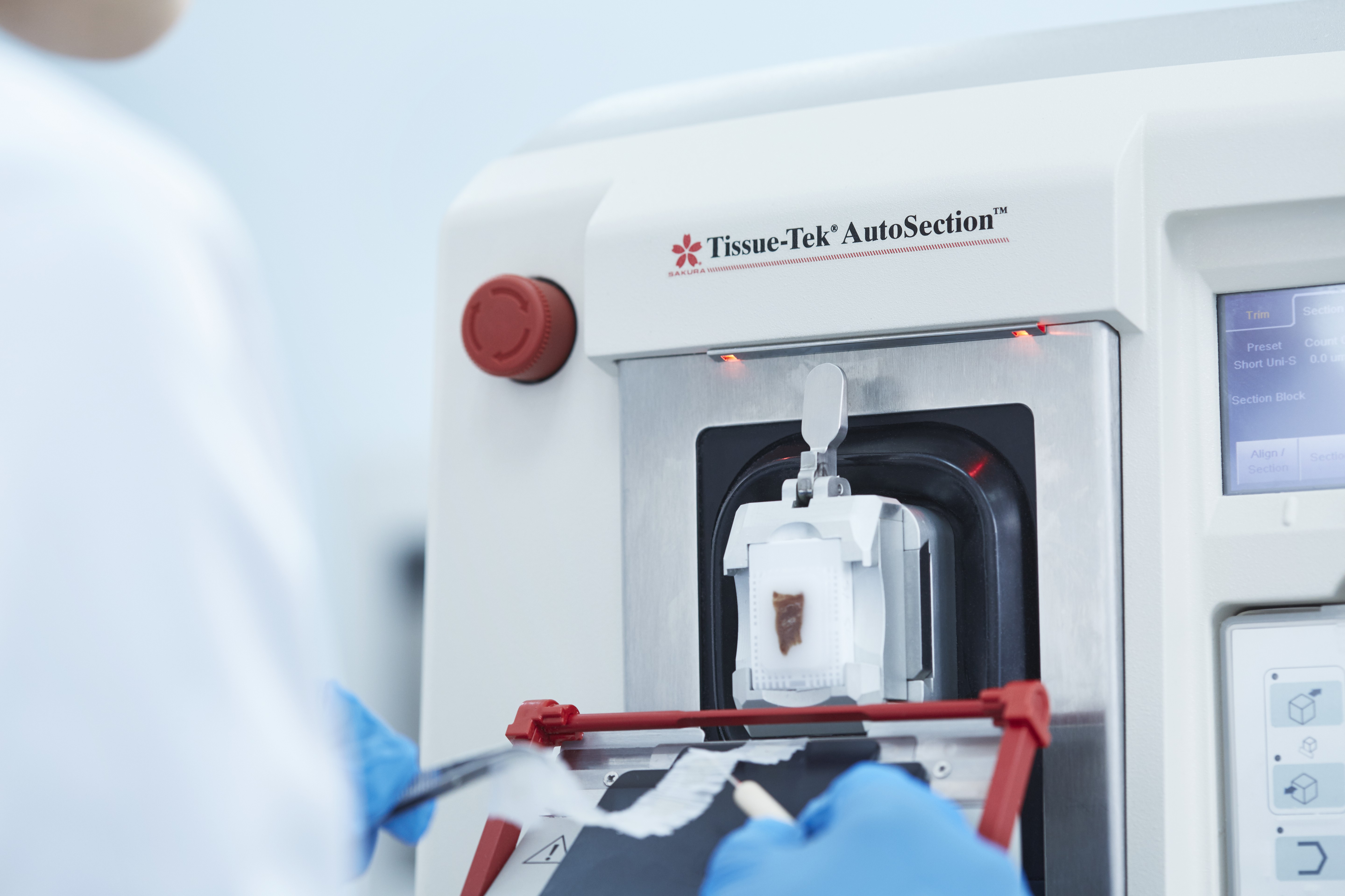 A person uses a Tissue-Tek AutoSection machine to prepare a tissue sample for automatic sectioning in a lab setting.